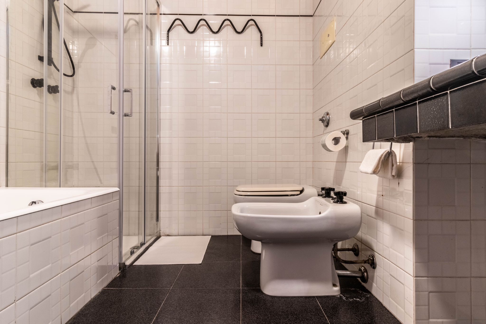 Bathroom with glass shower, bidet, toilet, and tiled floor