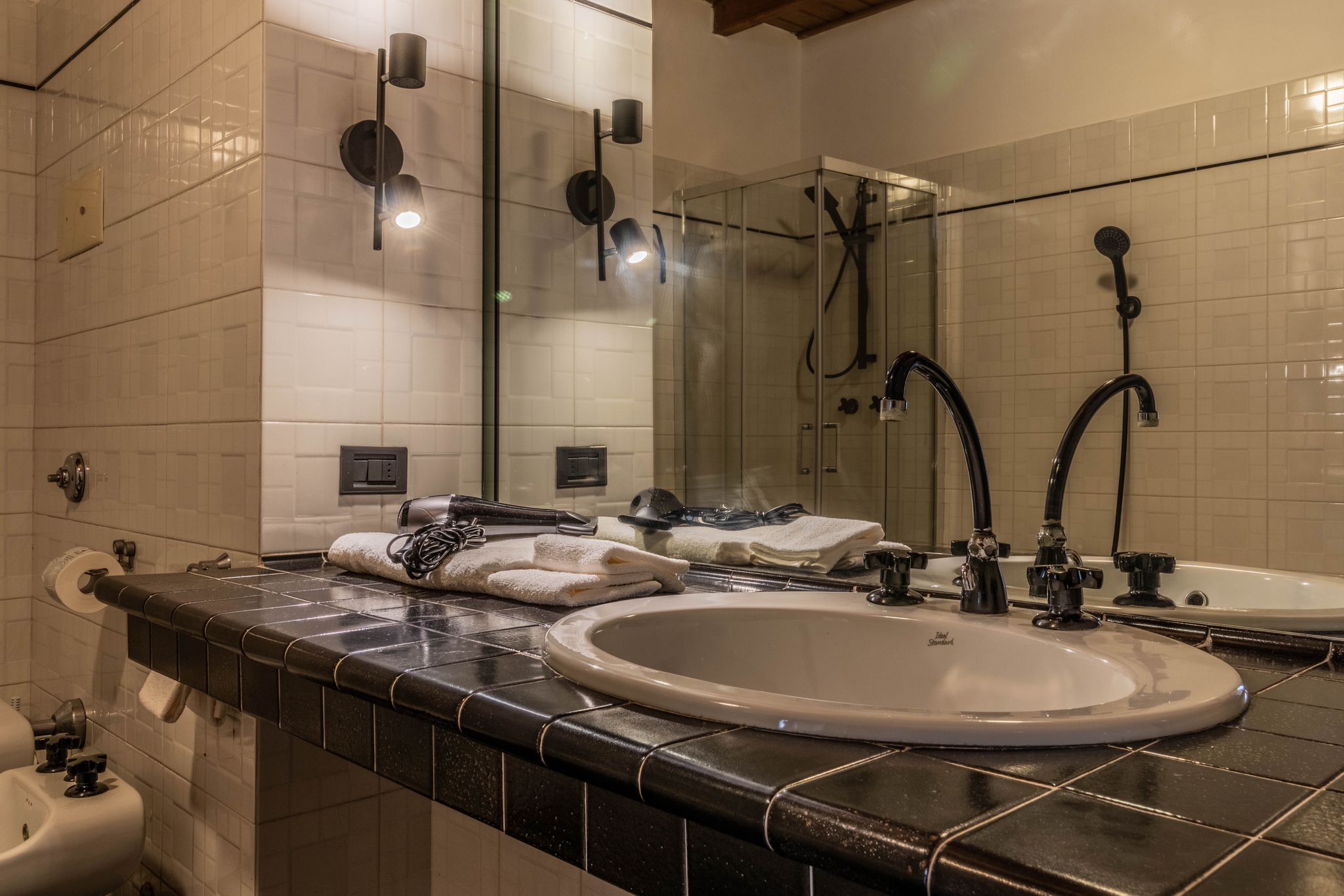 Bathroom sink and mirror with black tiled vanity
