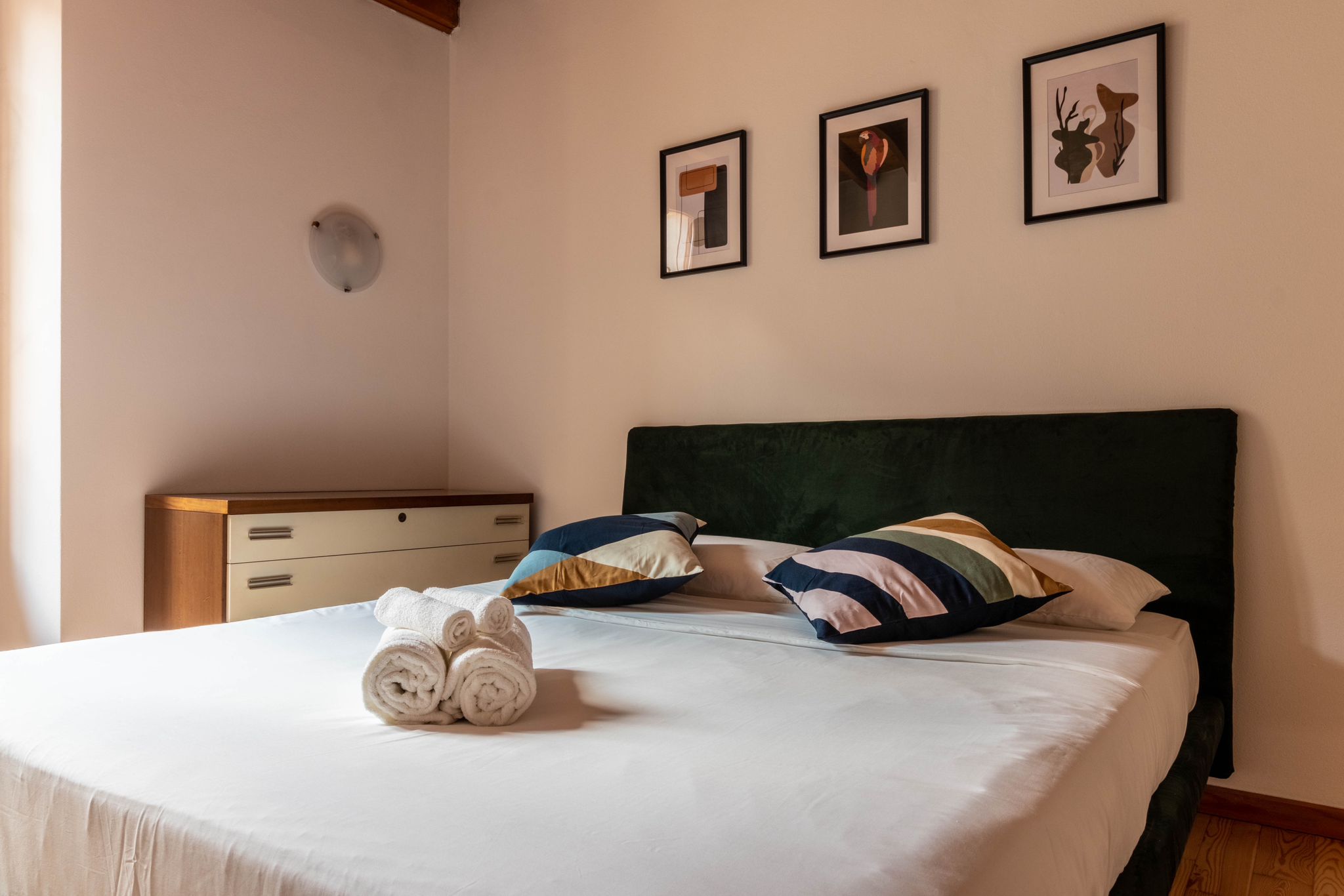 Guest bedroom bed with folded towels and framed artwork above the headboard