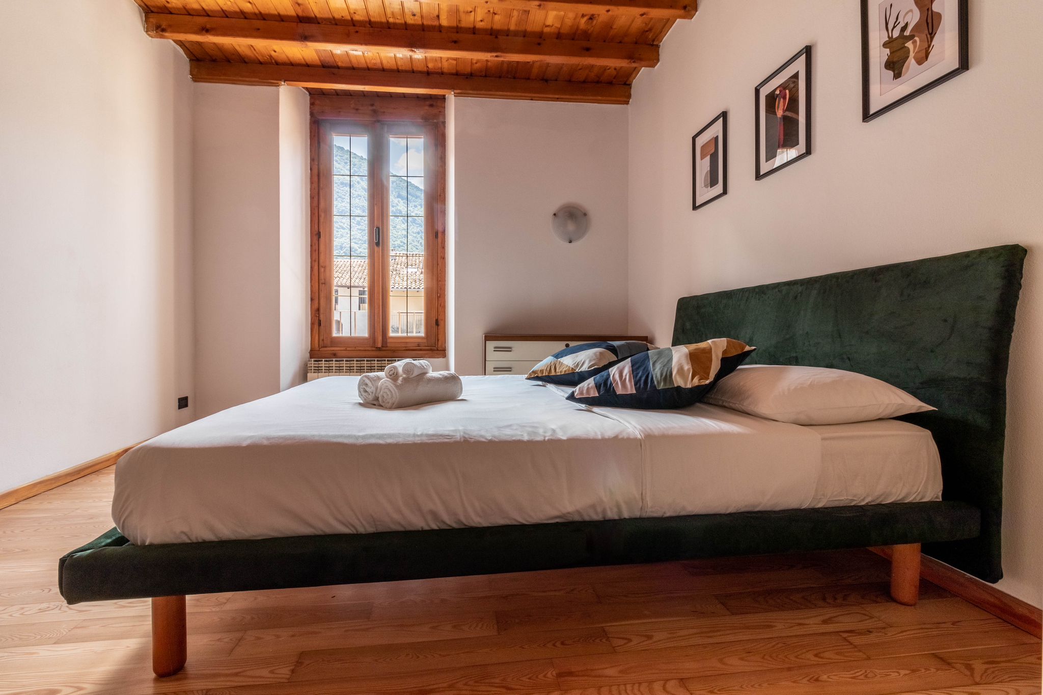 Guest bedroom with green bed and mountain view through the window