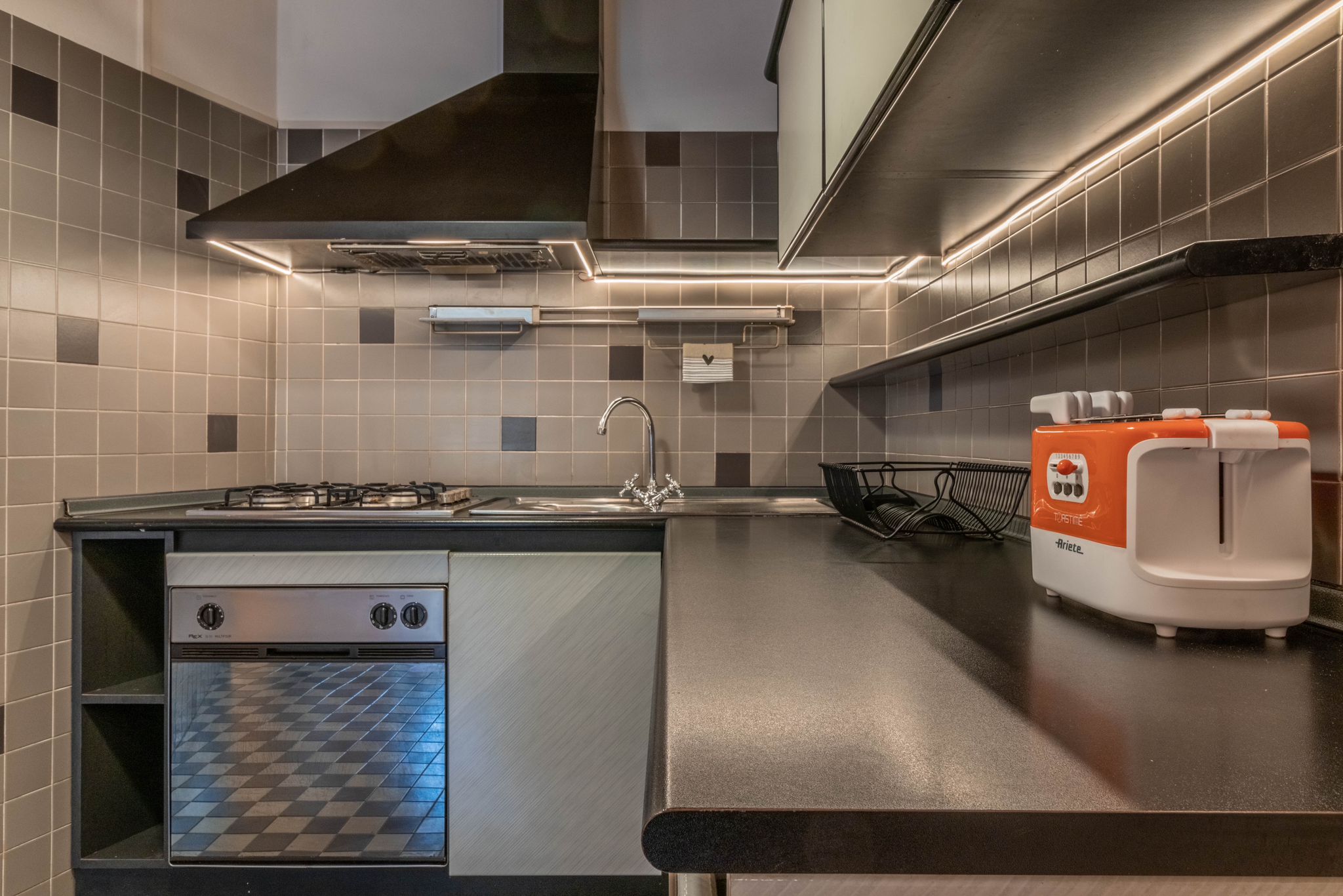 Kitchen counter with oven, gas hob, sink, and toaster