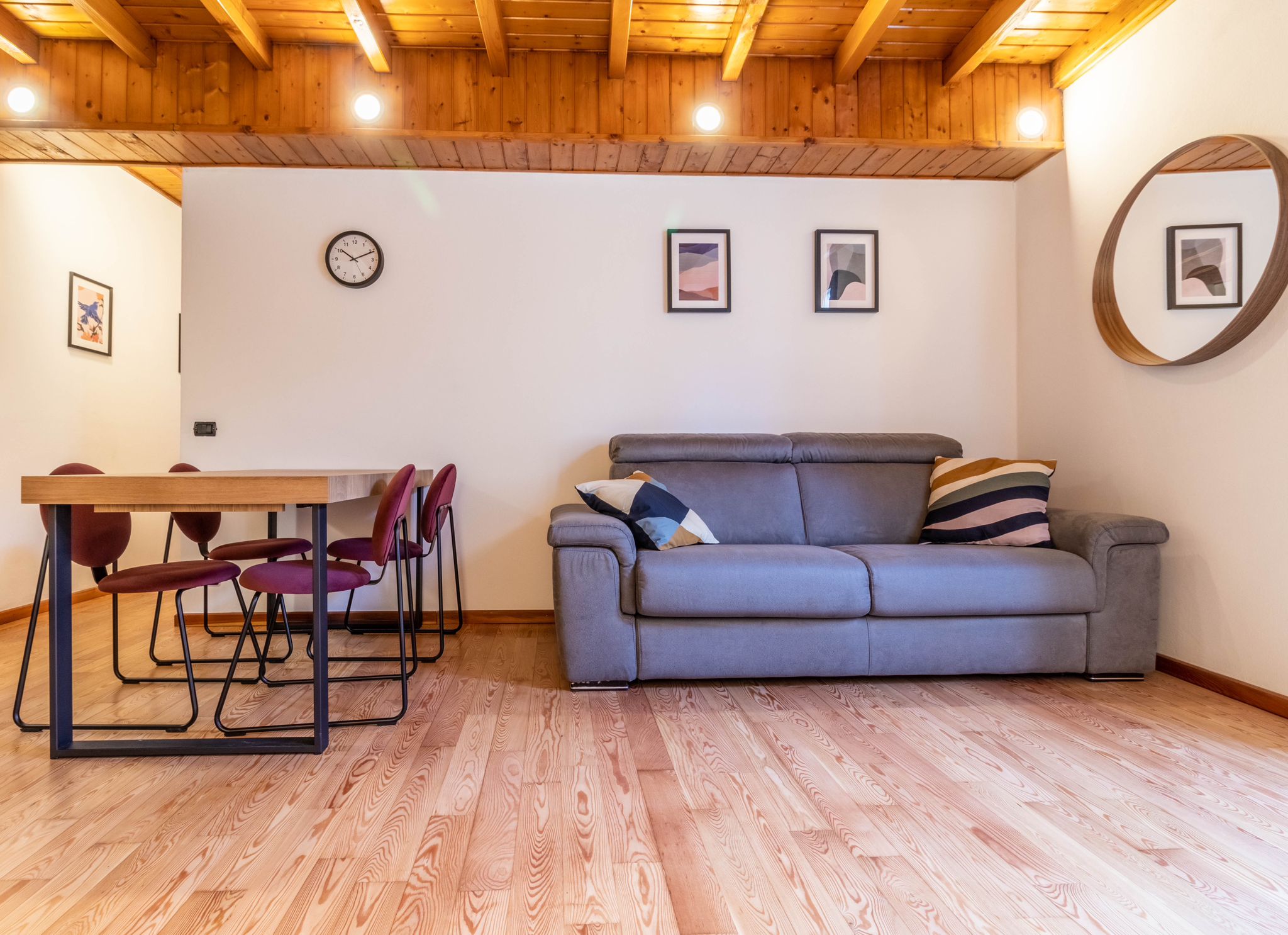 Living area with sofa and dining table beneath exposed beams