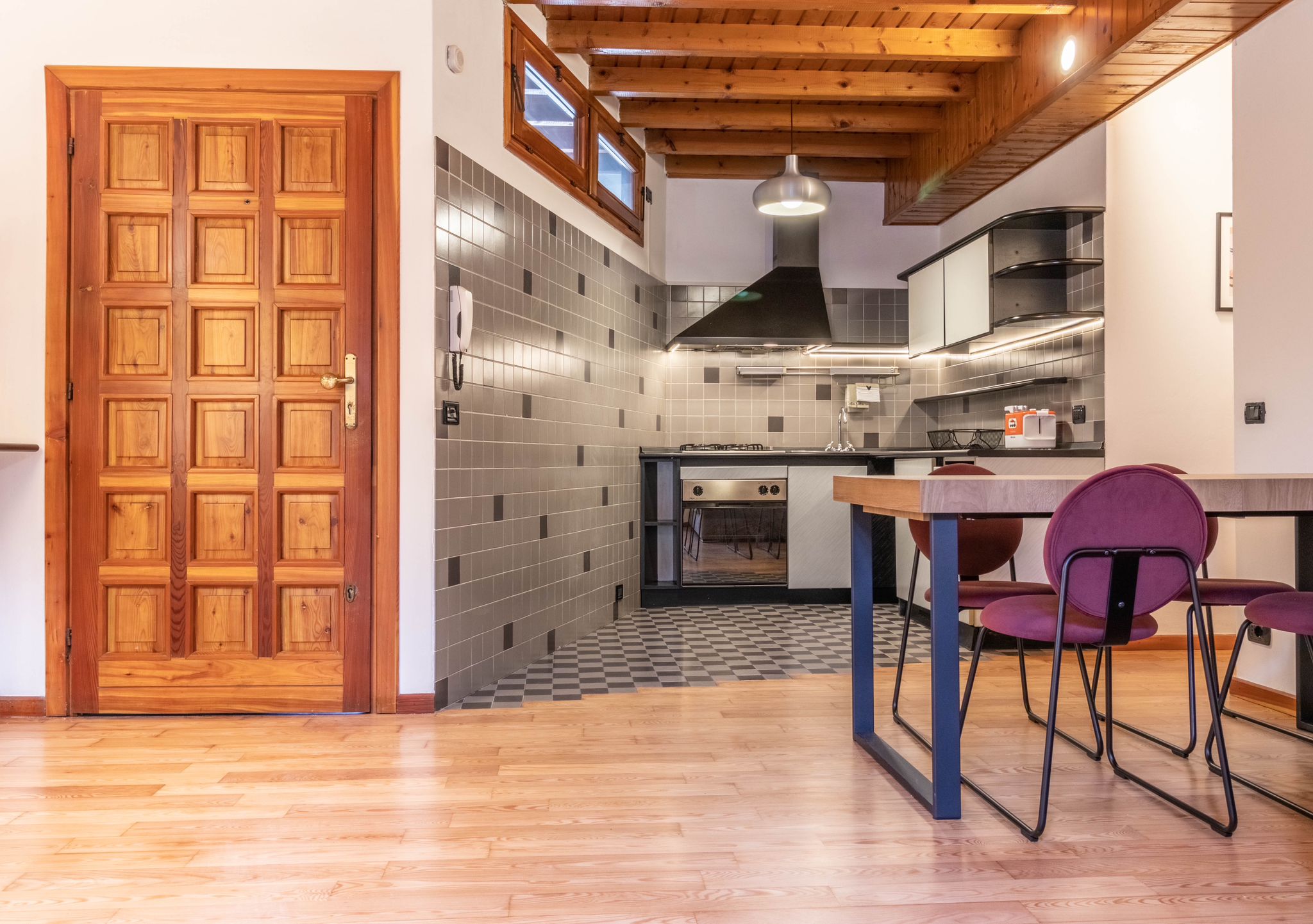 Open-plan kitchen and dining area with wood ceiling and dining chairs