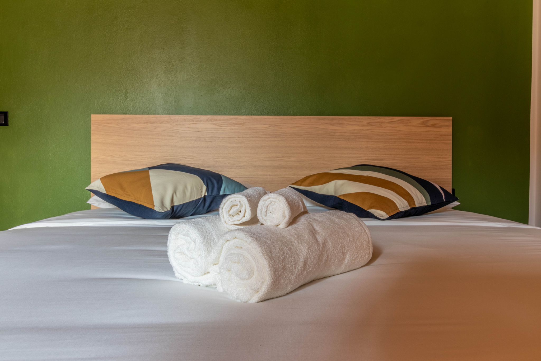 Primary bedroom bed with pillows and folded towels
