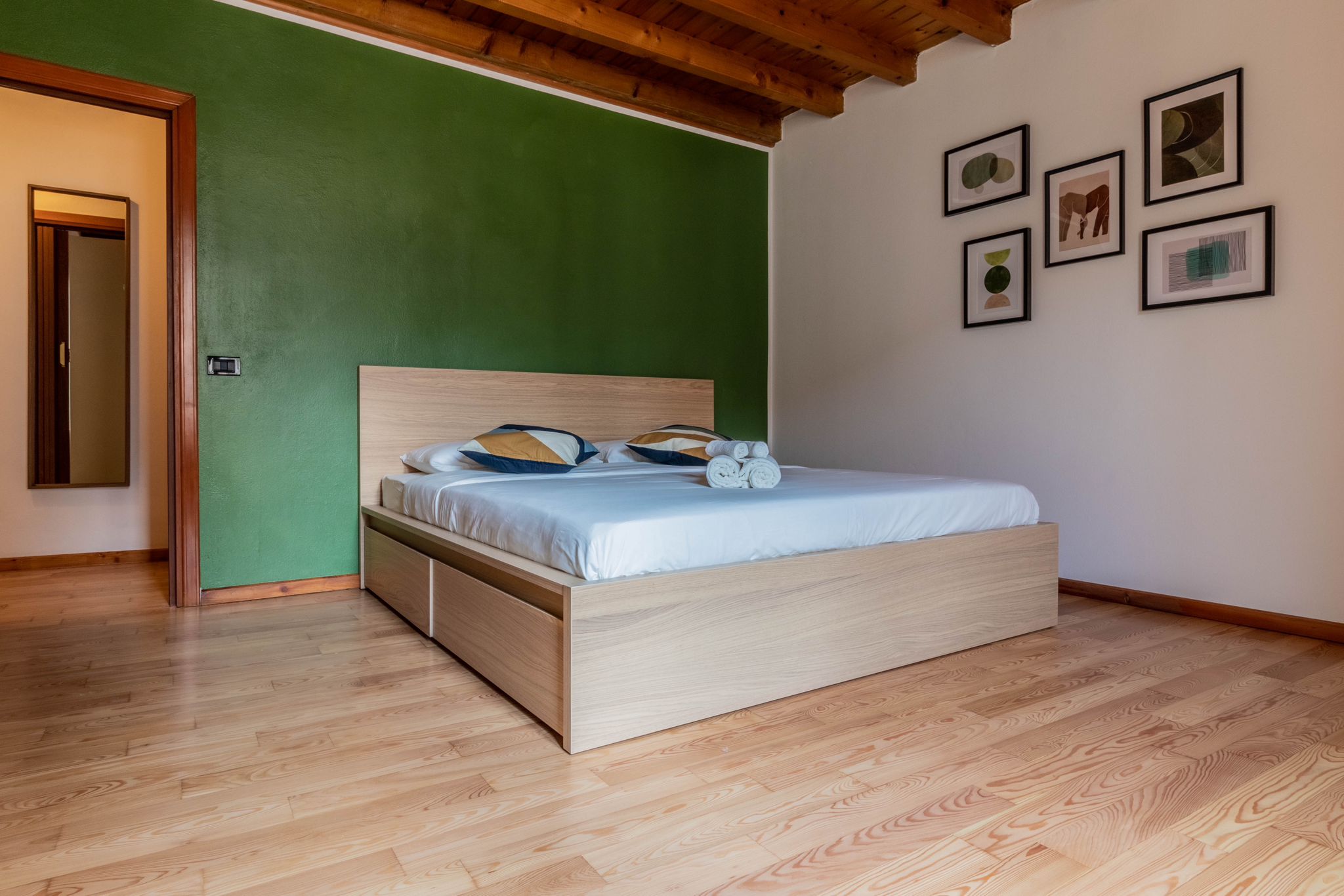 Primary bedroom with green accent wall, wood ceiling, and platform bed